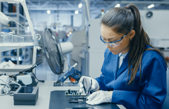Female engineer working on industrial machine in a laboratory.