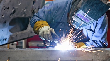 Un soudeur utilise une torche sur une pièce de voiture dans une usine automobile