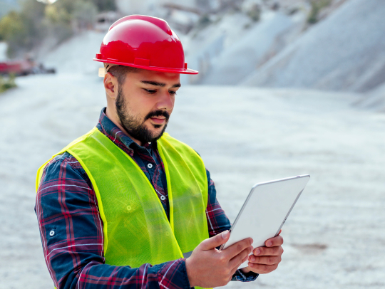 Ingénieur minier étudiant des documents de travail sur une tablette sur le site d’une mine