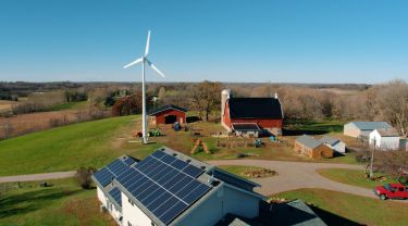 L’éolienne haute performance d’Eocycle érigée sur une ferme rurale, où des panneaux solaires sont installés sur le toit de la ferme.