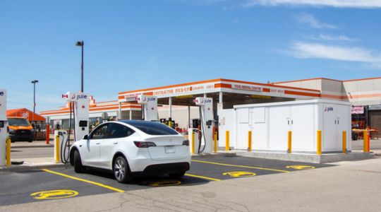 Un véhicule électrique branché à la station de recharge ultrarapide d’eCAMION dans un stationnement extérieur.