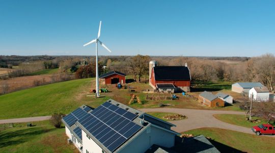 L’éolienne haute performance d’Eocycle érigée sur une ferme rurale, où des panneaux solaires sont installés sur le toit de la ferme.