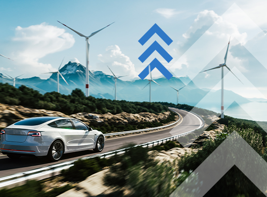 Une voiture électrique roule sur une route bordée d’éoliennes, avec des montagnes à l’horizon.