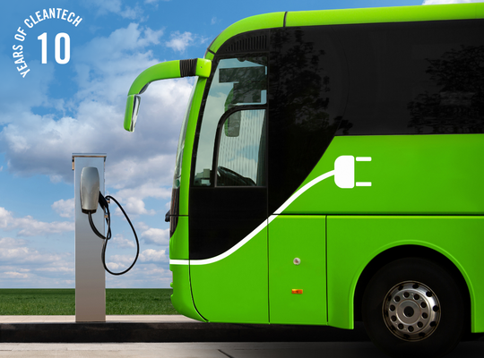 Green electric bus connected to a charger