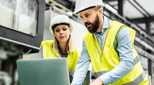 Image of two people looking at a computer in a warehouse