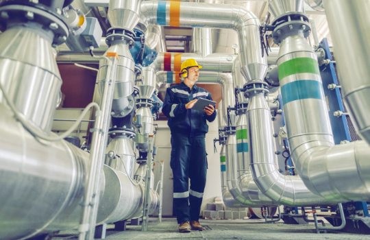 Industrial mechanical engineer holding tablet and inspecting HVAC heating ventilation air conditioning system and pipping line of industrial construction.