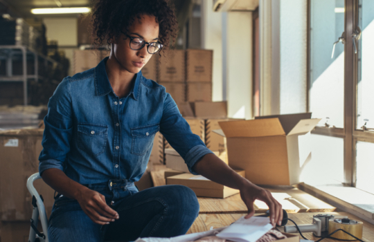 Female business owner packaging products into boxes