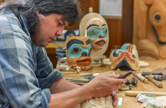 Indigenous man hand crafting wooden sculptures