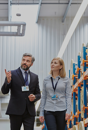 Un homme et une femme d’affaires visitent des installations de fabrication de fibre optique.