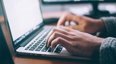 Closeup of hands typing on a laptop keyboard