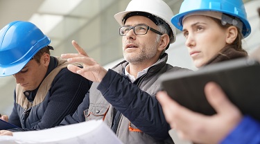 Two men in hardhats look over building plans