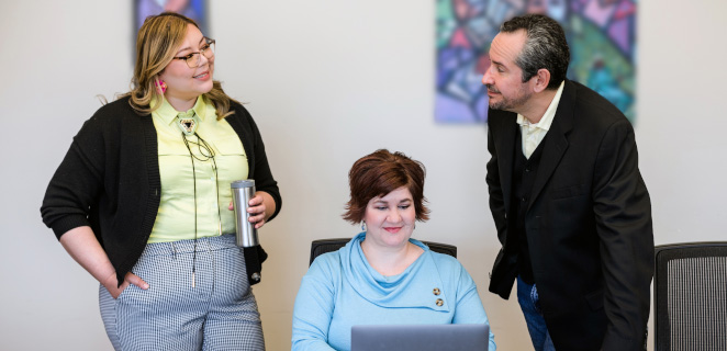 Deux femmes et un homme travaillent sur un ordinateur portable dans une salle de réunion