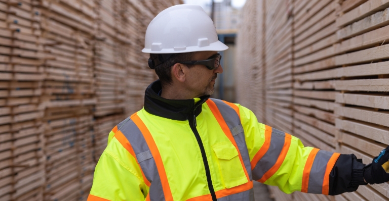 Al Balisky, president and CEO of Meadow Lake Tribal Industrial Investments, inspects stacks of finished lumber products.