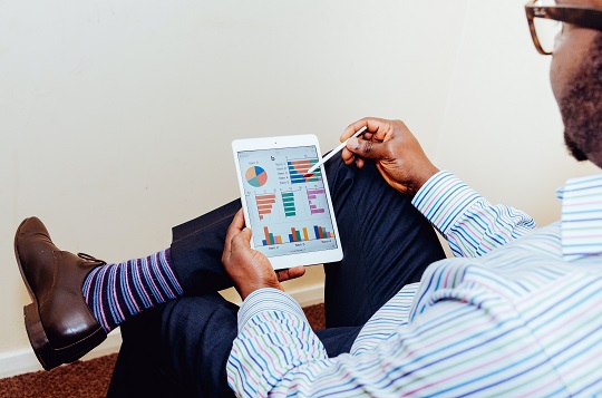 Un homme regarde des tableaux et des graphiques sur sa tablette.