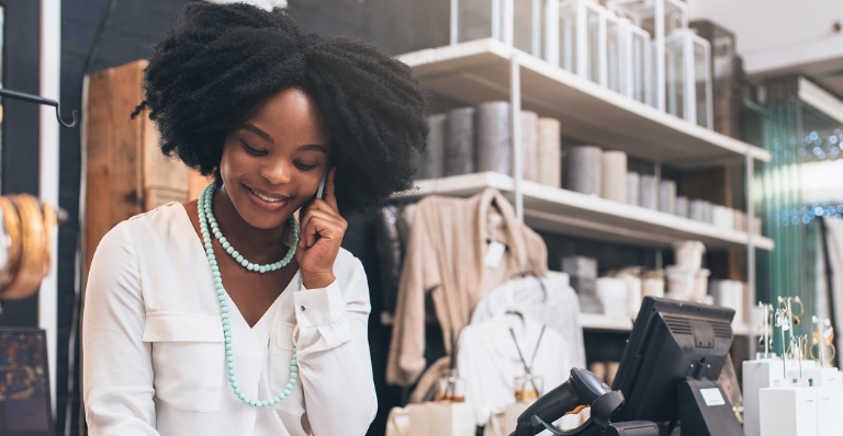 Black female storeowner taking a customer order over the phone.