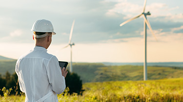 Engineer checks Wind Turbine system with a tablet. Alternative Energy. Wind farm. Clean renewable energy technologies. Wind power plants.