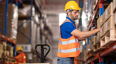 An employee is moving boxes in a big warehouse.