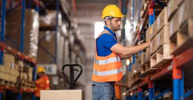 An employee is moving boxes in a big warehouse.