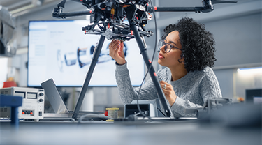 A black woman in tech is inspecting the bottom of a robotic innovation