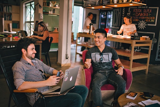 Deux hommes qui travaillent en souriant dans un café