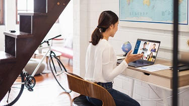 Femme assise à une table qui participe à une vidéoconférence