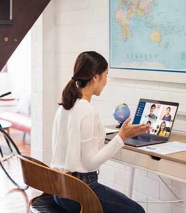 Femme assise à une table qui participe à une vidéoconférence