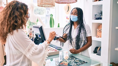 Une commerçante portant un masque sert des clients.