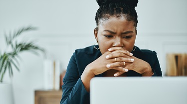 Woman looks confused as she reads a document on her office computer.