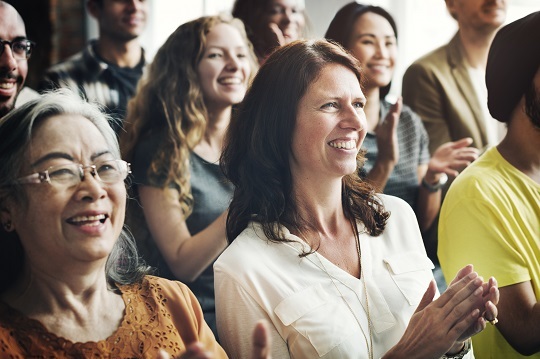 Diverse female audience clapping after presentation.