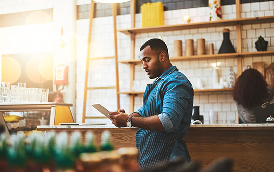 Photo of an entrepreneur using a digital tablet at his restaurant.