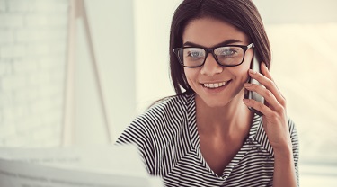Femme souriante consultant son ordinateur portable et parlant au téléphone avec un client