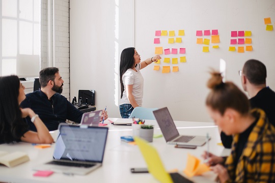 Woman puts sticky notes on classroom board