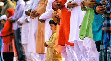 Small Indian boy stands with a row of men