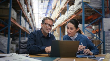 Warehouse team reviewing shipping and inventory data on a laptop