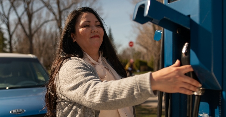 Woman plugging in her electric vehicle.