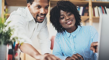 Two Black co-workers discuss startup partnership.