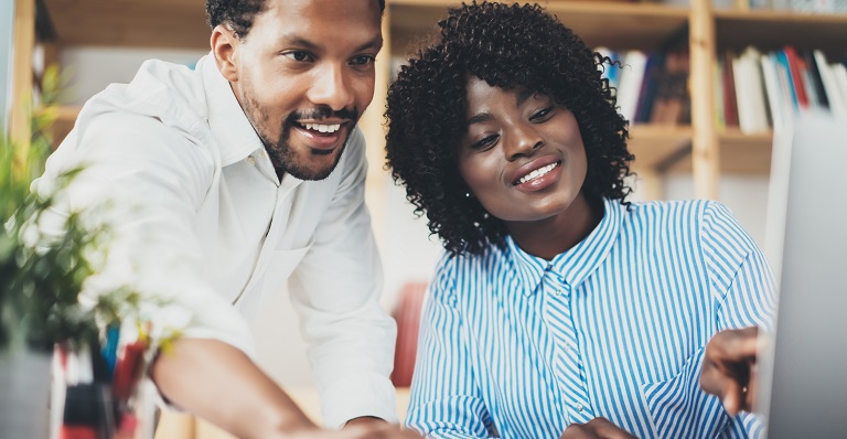 Two Black co-workers discuss startup partnership.