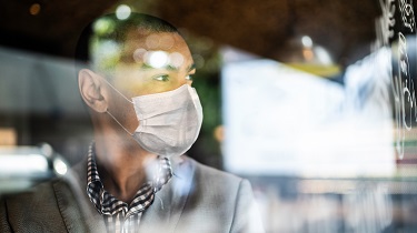 Un exportateur noir portant un masque regarde par la fenêtre de son bureau