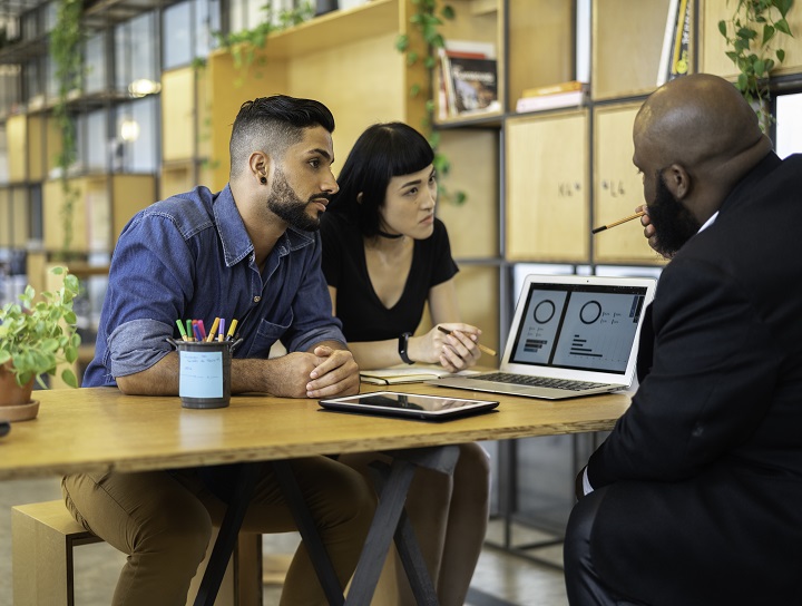 Male financial advisor explains pie graphs on the computer to concerned couple.