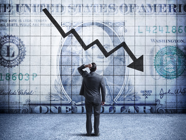 Businessman looks at oversized poster of American dollar bill with downward arrow, indicating declining worth.