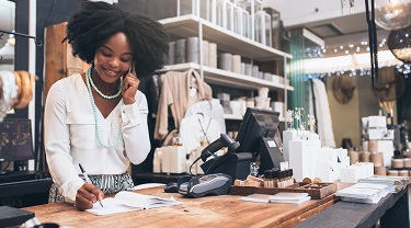 Femme noire propriétaire d’un magasin prenant la commande d’un client par téléphone