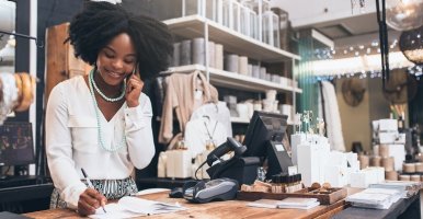 Femme noire propriétaire d’un magasin prenant la commande d’un client par téléphone