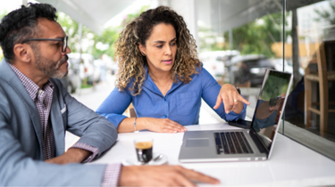 A businessman speaks on a web conferaence with an advisor using a laptop webcam