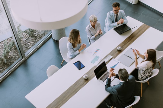 Vue aérienne d'employés de bureau frappant des mains autour d'une table de réunion.