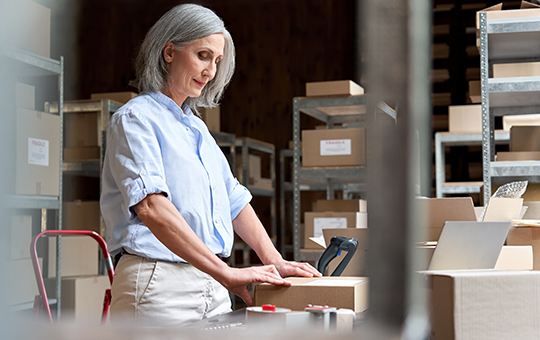 Mature female small business owner worker packing parcel