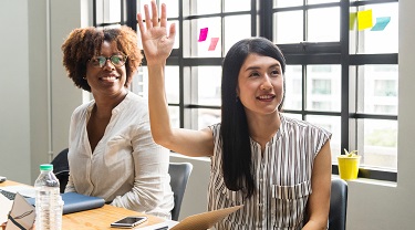 Asian woman raises her hand to ask a question during in-class training.