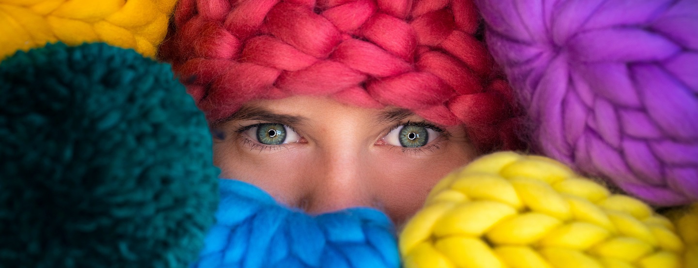Une entrepreneure observe de derrière ses stocks de laine colorée.