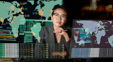 Jeune femme assise à un bureau devant un écran transparent avec carte du monde, chiffres et données.