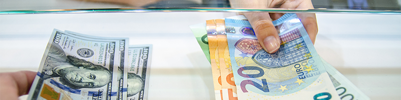 Two hands exchanging US dollars for euros