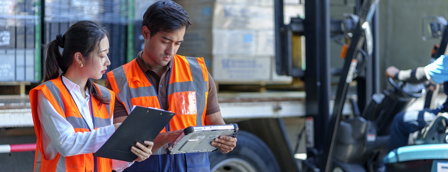 Les employés d'entrepôt vérifient les documents pendant que le chariot élévateur charge l'expédition dans un camion.